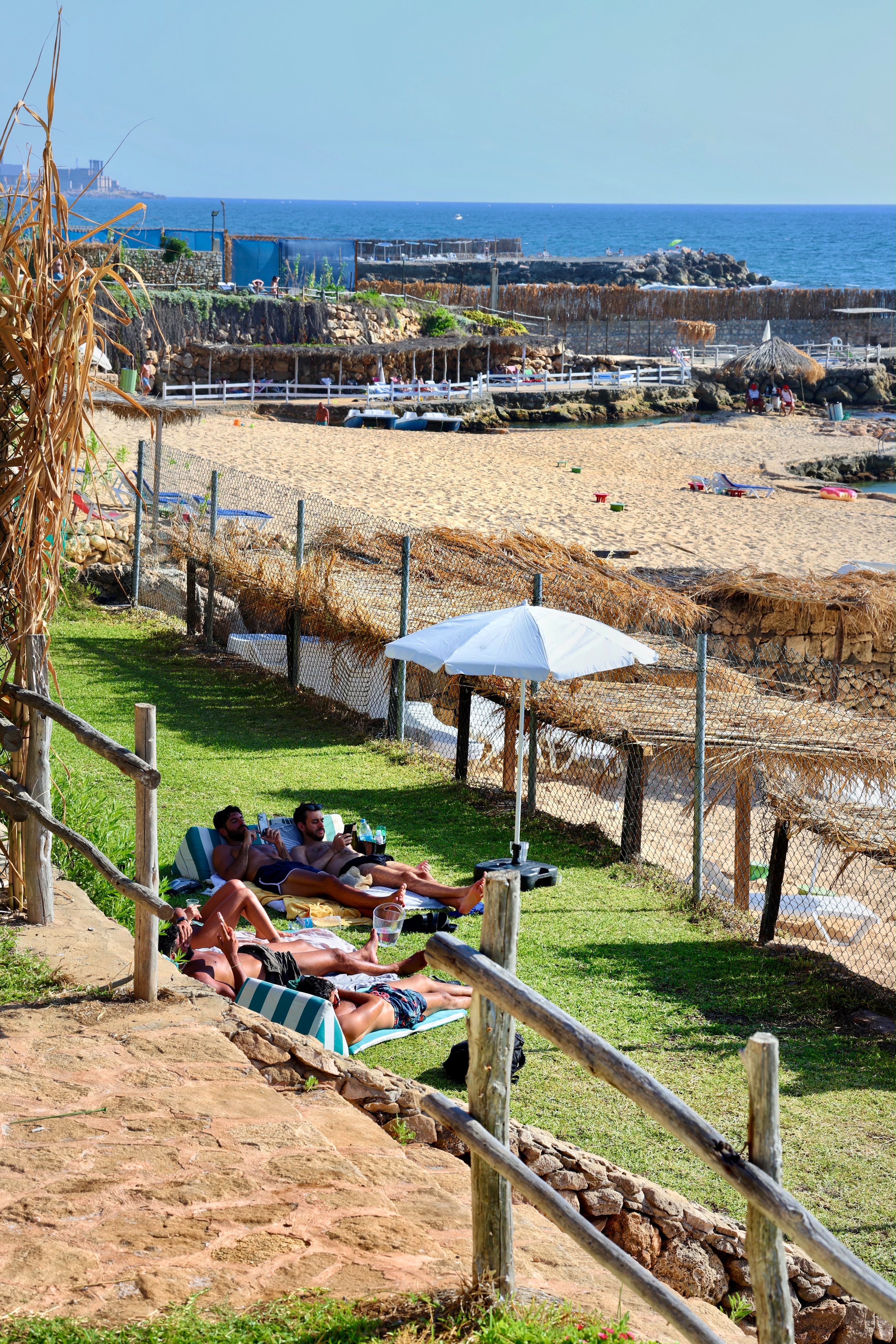 Guests relaxing on the garden lawn overlooking the beach at Side B